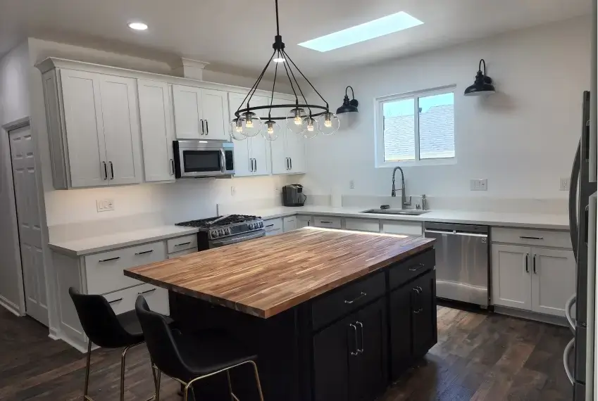 Modern kitchen with wooden island and chandelier.